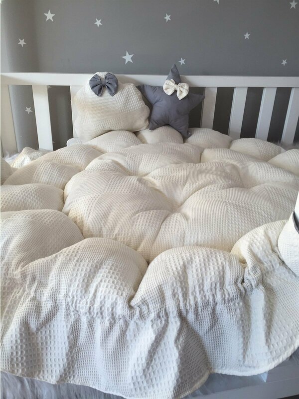 ที่นอนเด็กแบบพับเก็บได้ทำจากผ้าปิเก้ครีมแบบมีระบายออกแบบให้เป็นระบาย