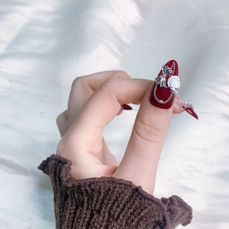 Manicure indossata a mano, ghiaccio rosso vino di lusso leggero attraverso camelia, diamanti e flash, unghie di mandorle di fascia alta fatte a mano