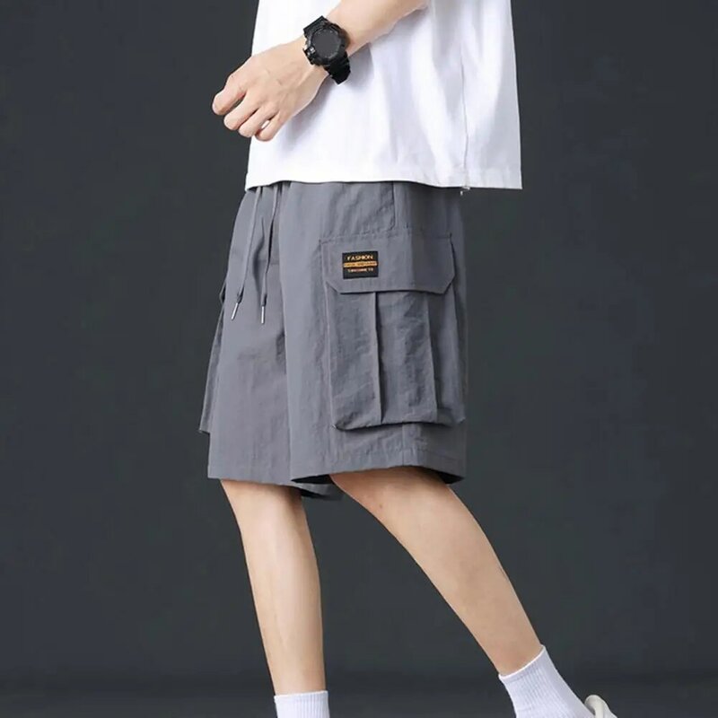 Calções de carga casual masculino de cor sólida com cintura com cordão, bolsos múltiplos para esportes, perna larga, comprimento do joelho