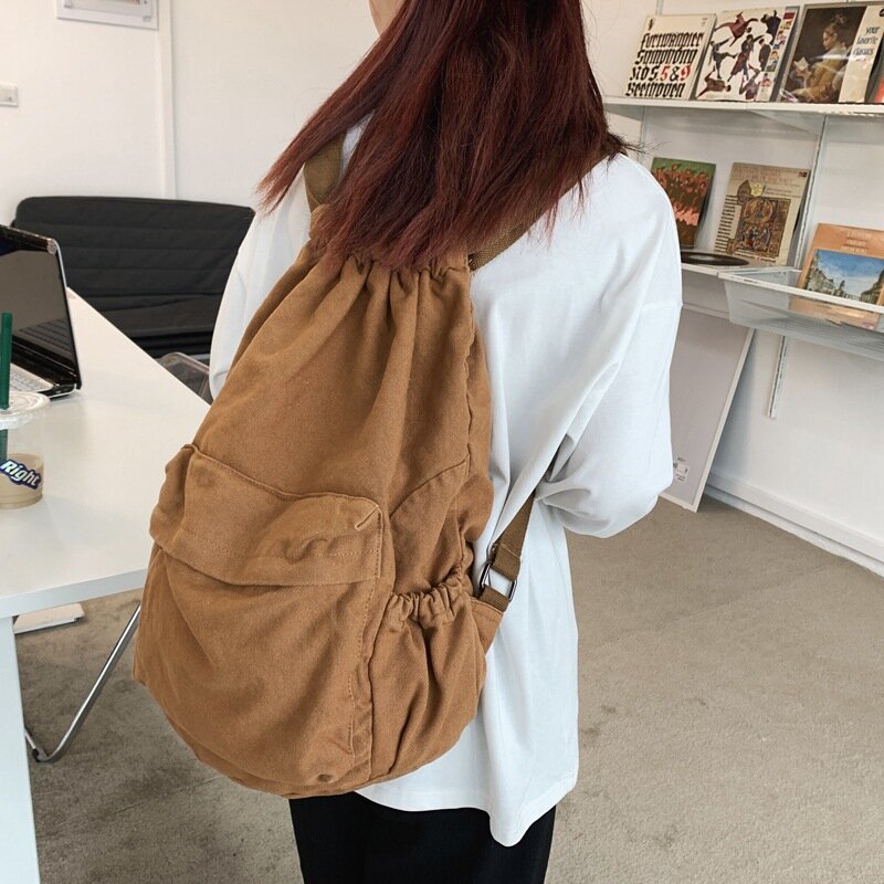 สาวสีทึบสไตล์วินเทจผ้าใบเกาหลีกระเป๋าเป้ผู้หญิงแบบลำลอง Harajuku นักเรียนม.ปลายล้างกระเป๋าเป้สะพายหลังผ้าใบแบบผูกเชือก