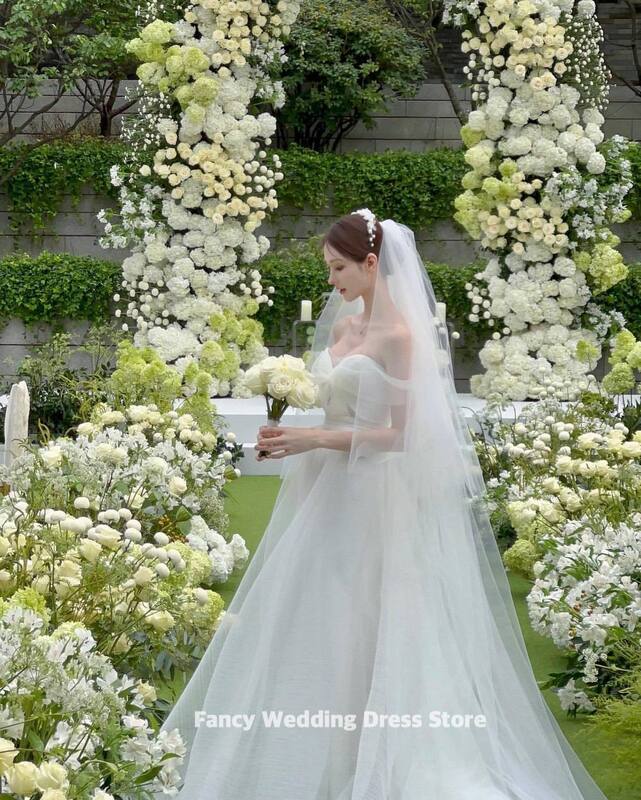 Um vestido de noiva sem mangas, extravagante simples fora do ombro, vestido de casamento coreano para foto, feito sob encomenda, até o chão