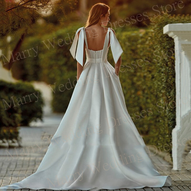 Nowoczesne proste suknie z kieszeniami ślubne z kokardą bez rękawów satynowe suknie ślubne bez pleców zapinane na guziki
