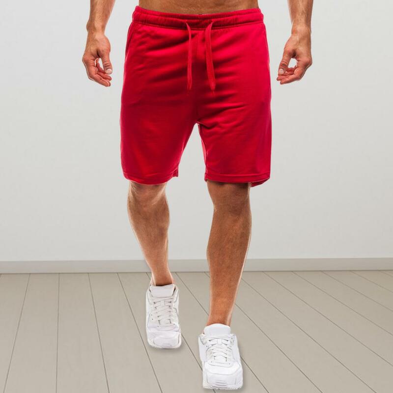 Celana pendek atletik pria, pakaian jalanan celana pendek olahraga kaki lebar lurus warna polos saku pinggang tali serut elastis musim panas