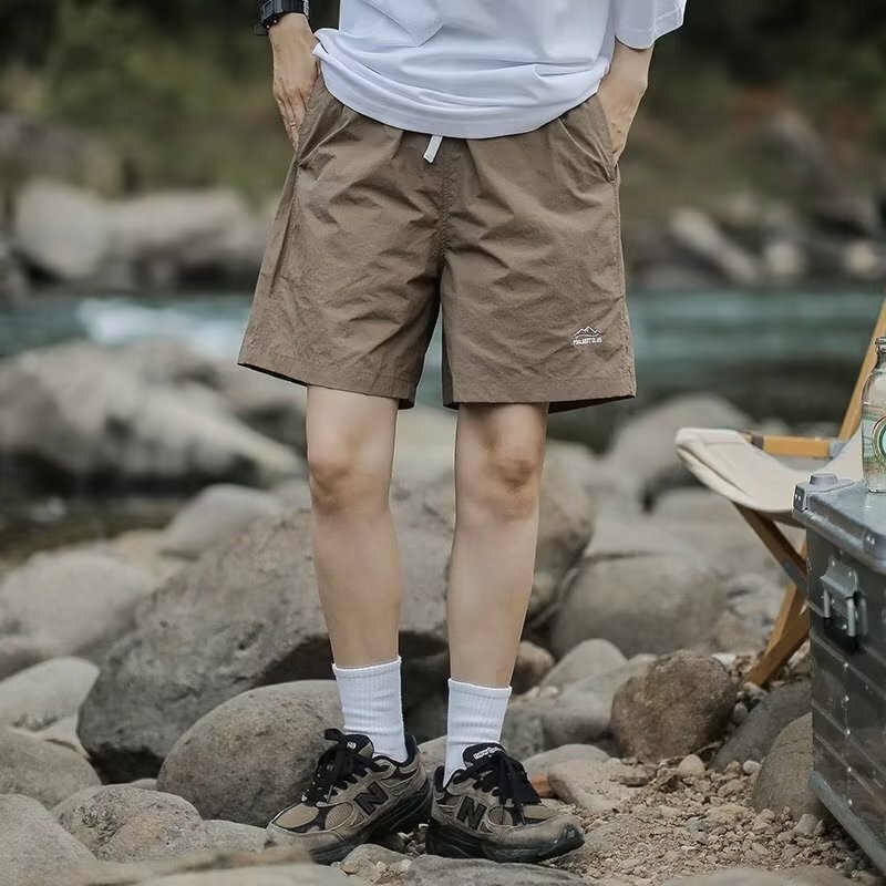 Celana olahraga pria, celana pendek lurus longgar modis bercetak saku serut pinggang sedang elastis tambal sulam untuk lelaki musim panas