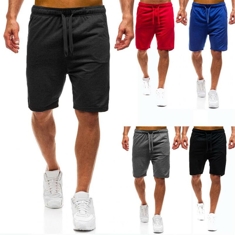 Celana pendek atletik pria, pakaian jalanan celana pendek olahraga kaki lebar lurus warna polos saku pinggang tali serut elastis musim panas