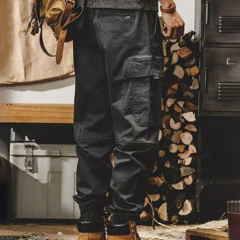 Elegante calça cargueira masculina com múltiplos bolsos, elástico na cintura, design em faixas de tornozelo, diariamente, rua alta, ao ar livre