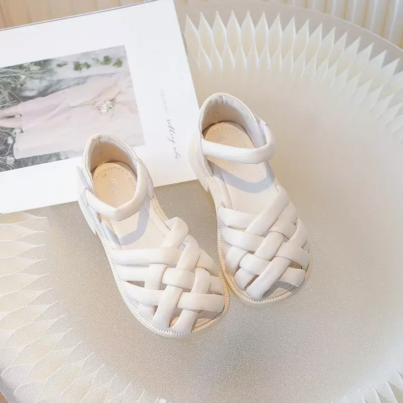 Nowe dziecięce sandały jednokolorowe dziewczęce letnie buty modne w stylu plecione dla dzieci przyczynowe plażowe rzymskie sandały na płaskim obcasie miękkie pokryte palcami