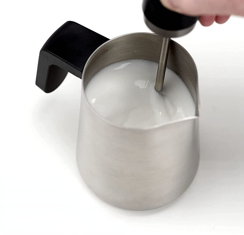 Frullino per il latte elettrico con gorgogliatore di latte tenuto in mano